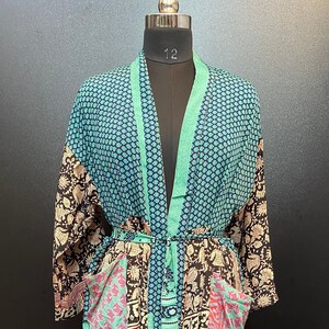 May include: A long, patterned robe with a teal, black, and maroon design. The robe features a floral and geometric pattern, with pockets and a matching belt. The robe is displayed on a mannequin.