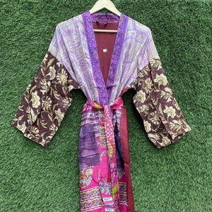May include: A long, purple, pink and brown silk robe with a floral pattern. The robe has a sash tie and long sleeves.