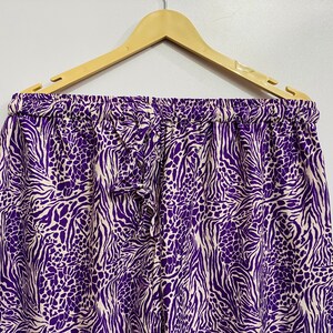 May include: Purple and white animal print pants with a drawstring waist.