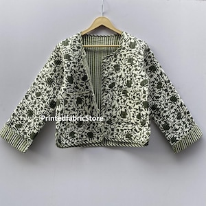 May include: A green and white floral print quilted jacket with a striped lining. The jacket has a rounded neckline and three-quarter sleeves.