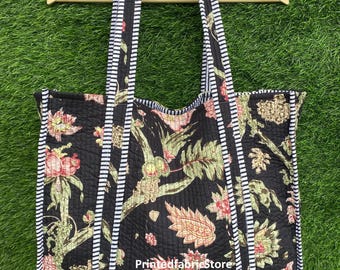 Op de afbeelding: Zwarte tote bag met een bloemenprint en witte en zwarte gestreepte afwerking. De tas heeft twee lange hengsels en de tekst "PrintedfabricStore" is zichtbaar aan de voorkant.