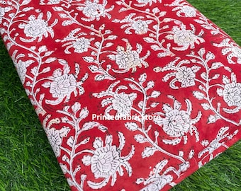 Pode incluir: Tecido de algodão vermelho com estampa floral branca. O tecido está dobrado ao meio e tem uma borda branca.