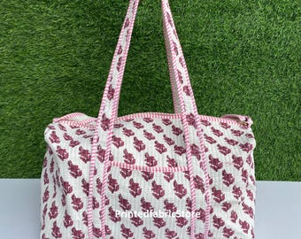 May include: White and pink cotton tote bag with a floral print and pink and white striped trim. The bag has two handles and a zipper closure. The text "Printedfabricstore" is printed on the bag.