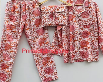 May include: A white pajama set with a pink and orange floral print. The set includes a long-sleeved shirt with a button-up front and matching pants.