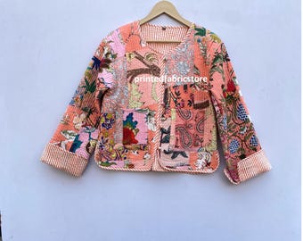 Op de afbeelding: Een roze gewatteerd jack met een bloemenprint en een knoopsluiting. Het jack heeft een patchwork-ontwerp en een wit en roze gestreepte afwerking.