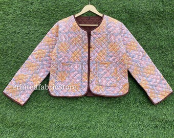 May include: A quilted jacket with a floral pattern in shades of pink, yellow, and blue. The jacket has a brown trim, two pockets, and a button-up front. The text "PrintedfabricStore" is visible on the bottom left.