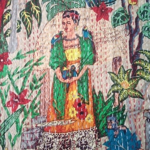 Puede incluir: Una colcha kantha colorida con un retrato de Frida Kahlo rodeada de plantas y p&aacute;jaros tropicales. La colcha est&aacute; hecha de algod&oacute;n y tiene un dise&ntilde;o cosido a mano.