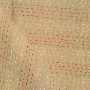 Puede incluir: Tela beige con un patr&oacute;n de cuadr&iacute;cula de puntadas rojas y blancas.