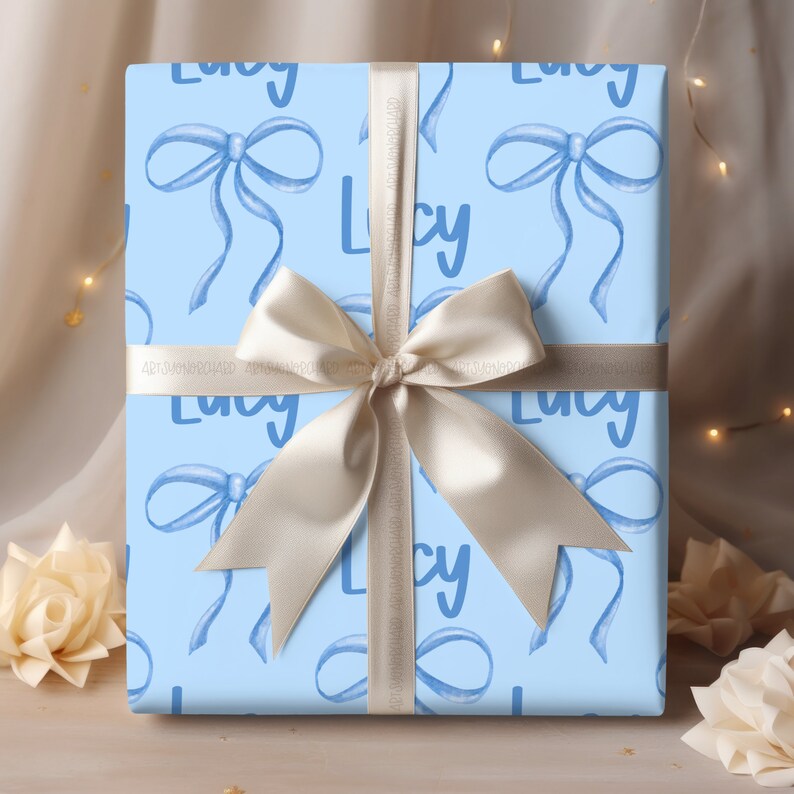 May include: Light blue gift wrap with a white ribbon and a repeating pattern of blue bows and the name "Lucy" in white.
