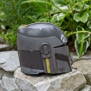 May include: A black and yellow helmet with a weathered, distressed look. The helmet has a visor and a raised detail on the side.