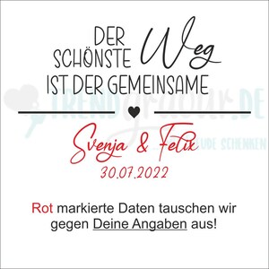 May include: A white card with black text that reads "Der sch&ouml;nste Weg ist der gemeinsame" with a black heart symbol. Below the text is the names "Svenja & Felix" in red cursive writing and the date "30.07.2022". The text "Rot markierte Daten tauschen wir gegen Deine Angaben aus!" is in red text.