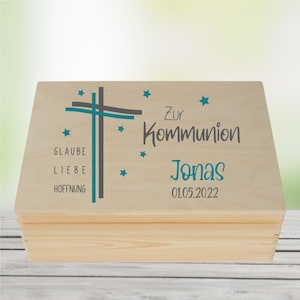 Könnte beinhalten: Holzkiste mit einem Kreuzdesign und den Worten "Zur Kommunion Jonas 01.05.2022" auf dem Deckel. Das Kreuz besteht aus grauen und türkisblauen Linien mit türkisblauen Sternen drumherum. Die Worte "Glaube Liebe Hoffnung" stehen unter dem Kreuz.