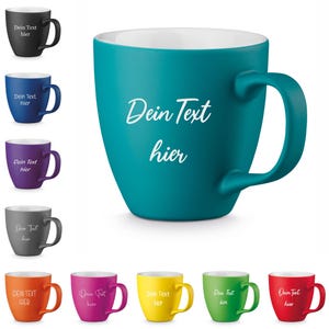 Könnte beinhalten: Eine Auswahl an farbigen Keramikbechern, darunter Schwarz, Blau, Lila, Grau, Orange, Pink, Gelb, Grün und Rot. Jeder Becher hat einen weißen Innenraum und einen großen Henkel. Der Text "Dein Text hier" ist auf der Vorderseite jedes Bechers aufgedruckt.