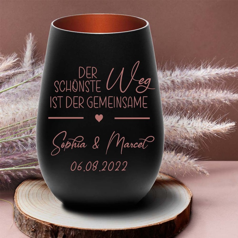 May include: A black glass with a copper rim, featuring the text "Der sch&ouml;nste Weg ist der gemeinsame" and a heart symbol. Below the text is "Sophia & Marcel" and the date "06.08.2022".