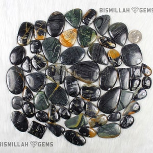 May include: A collection of 30 black, green, and yellow patterned stone cabochons. The stones are various shapes and sizes, and are arranged in a circle on a white background. BISMILLAH GEMS is printed at the top and bottom of the image.