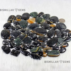 May include: A collection of black, green, and yellow gemstone cabochons. The stones are smooth and polished, with a variety of patterns and textures. BISMILLAH GEMS is printed on the image.