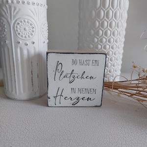 Peut inclure: Une pancarte en bois blanche avec du texte noir qui dit "Du hast ein Plätzchen in meinem Herzen".