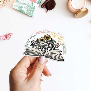 May include: A sticker with an open book and flowers, with the text "tune my heart to sing thy grace".