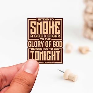 May include: A brown rectangular sticker with white text that reads "I intend to smoke a good cigar to the glory of God before I go to bed tonight. Charles Spurgeon."