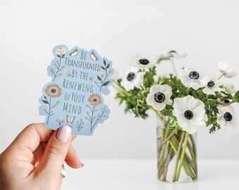 May include: A blue sticker with a floral design and the text "Be transformed by the renewing of your mind".