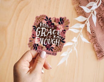 May include: A pink and brown floral sticker with the text "His Grace is Enough" and the scripture reference "2 Corinthians 12:9".