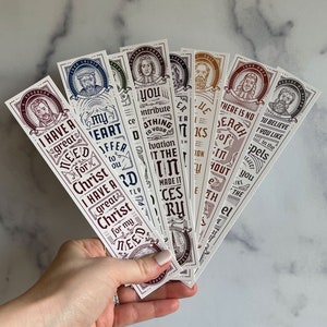 May include: A set of eight bookmarks with different quotes and illustrations. The bookmarks are printed on white cardstock with brown, red, and blue ink. The quotes include "I have a great need for Christ", "My heart I offer to you", "You contribute to a great salvation", "There is no death of sin without the el", "I believe in the gospels", "I have a great Christ for my need", "The books of the scriptures", and "All the works of the Lord are done with wisdom".