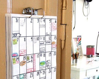 May include: A white calendar with black numbers and handwritten notes. The calendar is hanging on a door with a silver clip. The calendar is for September and shows the dates 1 through 27.
