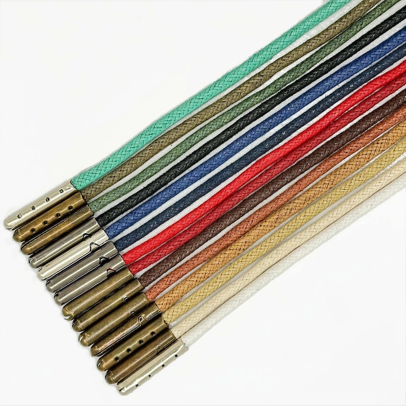 May include: A set of 15 colorful cotton cords with metal tips. The cords are arranged in a rainbow pattern, with the lightest colors at the top and the darkest colors at the bottom. The metal tips are all the same size and shape, and they are attached to the ends of the cords.