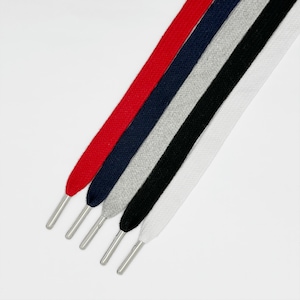 Puede incluir: Cinco cordones de zapatos en diferentes colores: rojo, azul marino, gris, negro y blanco. Los cordones son planos y tienen aglets metálicos.