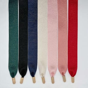 Puede incluir: Siete cintas de adorno de diferentes colores con puntas de metal dorado. Las cintas son verde, negra, azul marino, crema, rosa, rosa claro y roja.