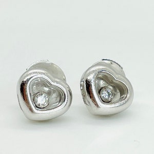 May include: A pair of silver heart-shaped earrings with a small diamond in the center of each heart.
