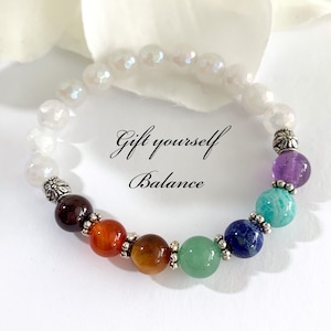 May include: A beaded bracelet with a variety of colorful gemstones, including amethyst, turquoise, and jade. The bracelet also features white, iridescent beads and silver-colored spacers. The text "Gift yourself Balance" is written on the image.