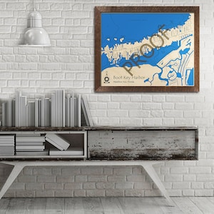 May include: A framed nautical chart of Boot Key Harbor in Marathon Key, Florida. The chart is printed on a cream-colored background with blue water and brown land features. The frame is dark brown wood.
