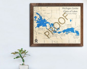 May include: A framed map of the Michigan Center Chain of Lakes in Jackson County, Michigan. The map shows the outlines of the lakes in blue, with the names of the lakes labeled. The map is on a beige background with brown lines and text.