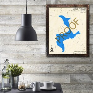 May include: A framed map of Lake Flower in Franklin and Essex Counties, New York. The map shows the lake's outline in blue, with surrounding roads and landmarks. The text "Lake Area - 166 acres" and "Deepest Point - 10 feet" is printed below the map.