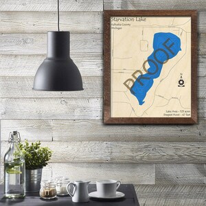 May include: A framed map of Starvation Lake in Kalkaska County, Michigan. The map shows the lake's depth contours and includes the text "Lake Area - 125 acres" and "Deepest Point - 47 feet".