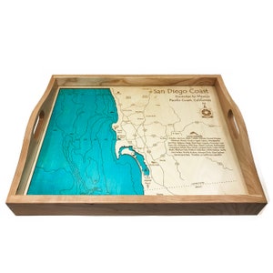 May include: A wooden serving tray with a blue and brown map of the San Diego Coast, Encinitas to Mexico, Pacific Coast, California. The tray has two handles and a compass design in the upper right corner.