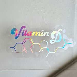May include: A holographic sticker with the text "Vitamin D" in a rainbow font and a chemical structure of vitamin D.