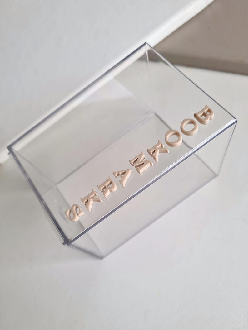 May include: A clear plastic box with the word "remarkable" spelled out in beige letters.