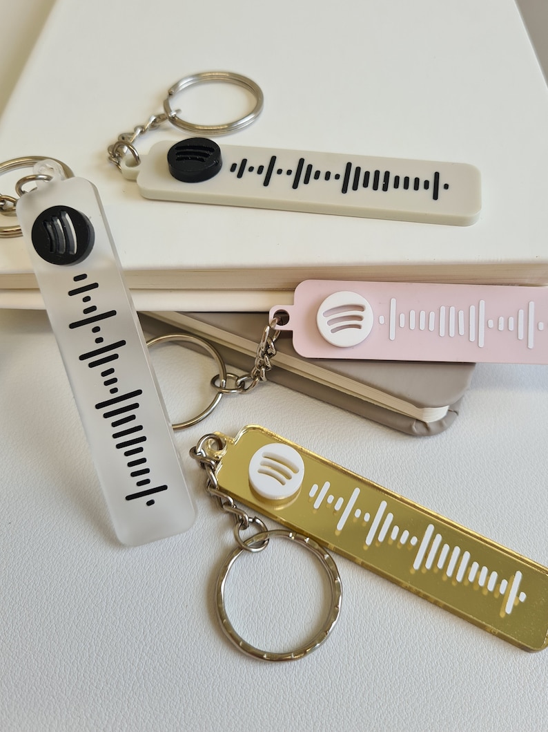 Puede incluir: Llaveros en varios colores, incluyendo transparente, rosa y dorado, cada uno con un dise&ntilde;o de c&oacute;digo Spotify. Los llaveros tienen un anillo de metal y un logotipo de Spotify. Los llaveros son rectangulares.
