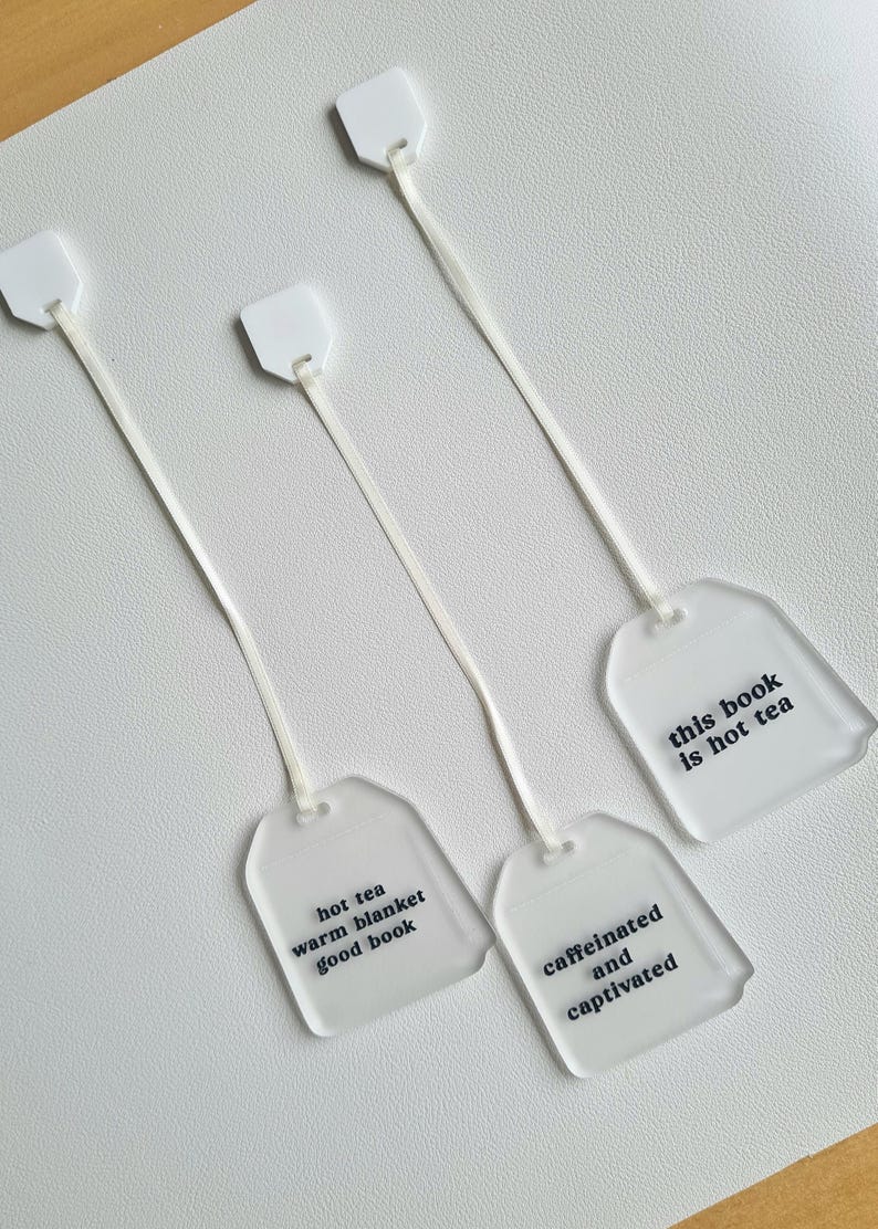 Puede incluir: Cuatro marcap&aacute;ginas transparentes con forma de bolsita de t&eacute; con cuerdas blancas. Cada marcap&aacute;ginas tiene una frase diferente impresa en negro: "hot tea warm blanket good book", "caffeinated and captivated" y "this book is not tea".
