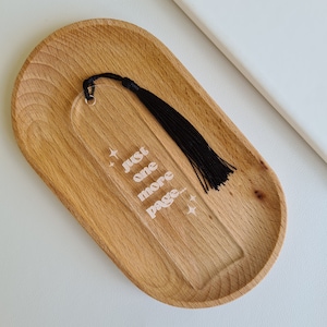 May include: A clear acrylic bookmark with a black tassel. The bookmark has the text "Just one more page..." with stars on either side.