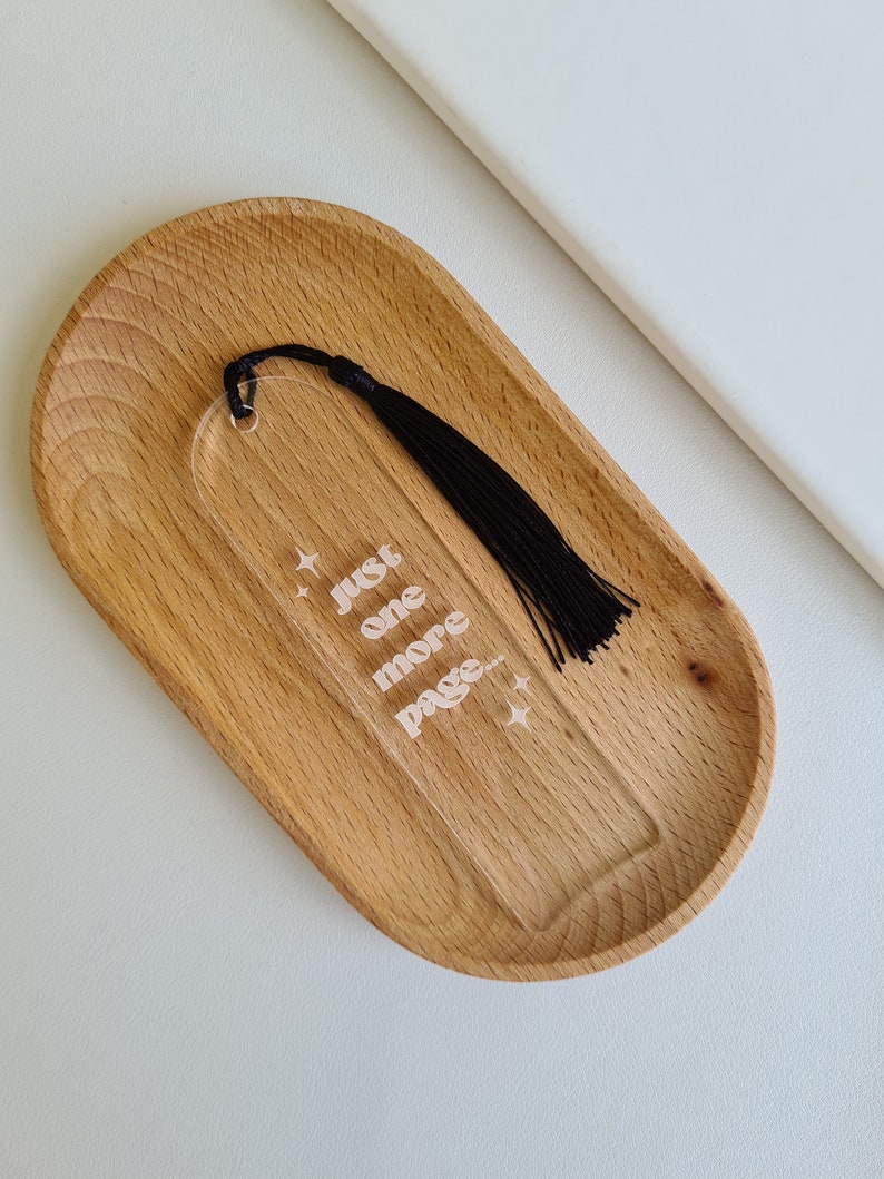 May include: A clear acrylic bookmark with a black tassel. The bookmark has the text "Just one more page..." with stars on either side.