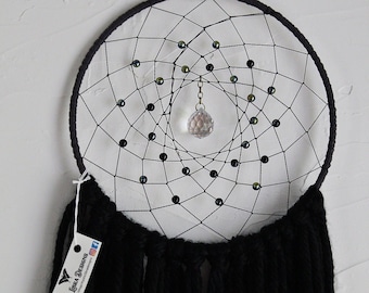 May include: Black dreamcatcher with a crystal hanging from the center. The dreamcatcher has black beads and a black fringe.