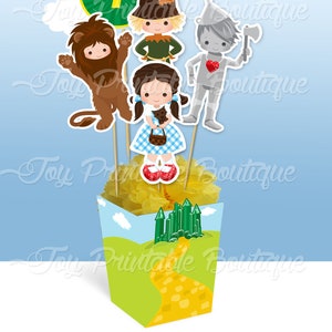 May include: A Wizard of Oz themed centerpiece featuring character cutouts including Dorothy, the Tin Man, Scarecrow, Lion, and a number 7. The centerpiece is in a decorative box with a yellow brick road and Emerald City design. Text reads "CENTERPIECE" and "Wizard of Oz".