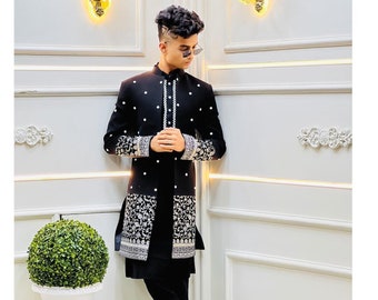 May include: A black long-sleeved jacket with silver embroidery and a black long-sleeved shirt underneath. The jacket has a mandarin collar and a button closure. The person is wearing black pants and black shoes.