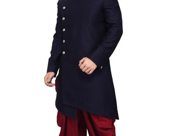 Könnte beinhalten: Eine dunkelblaue, langärmelige Kurta mit Stehkragen und silbernen Knöpfen. Die Kurta ist asymmetrisch und hat einen langen, fließenden Saum. Das Model trägt eine marone Dhoti-Hose und schwarze Schuhe.