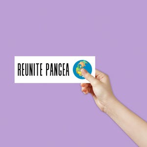 Op de afbeelding: Een witte kaart met de tekst "REUNITE PANGEA" in zwarte letters. Aan de rechterkant van de kaart staat een cartoonafbeelding van de aarde.