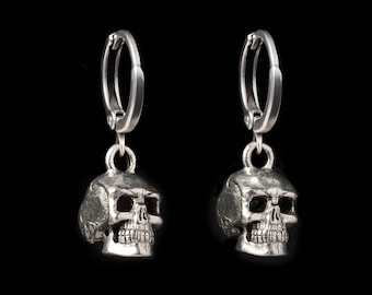 Può includere: Un paio di orecchini a cerchio in argento a forma di teschio. Gli orecchini sono in metallo e presentano un design di teschio dettagliato.