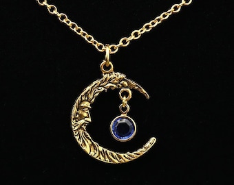 May include: A gold crescent moon necklace with a dangling blue crystal pendant.